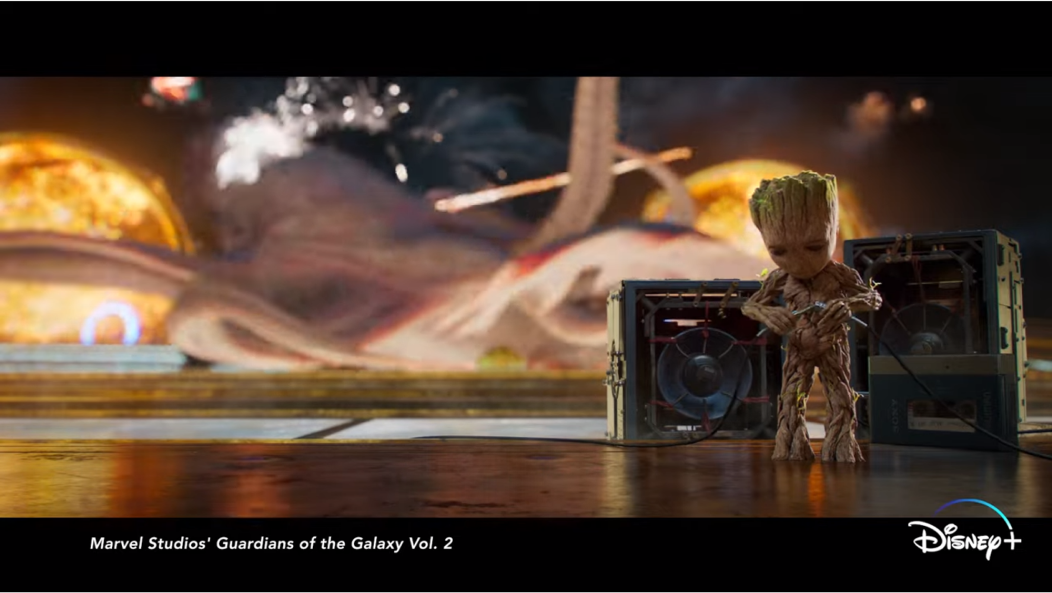 marvel studios’ Guardians of the Galaxy Vol.2, 그루트가 문어 괴물과 전투 중인 가오갤 멤버들을 등지고 스피커를 연결하고 있는 장면