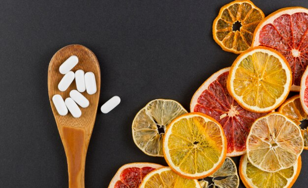 같이 먹으면 안되는 영양제 조합인 비타민과 고함량 비타민C가 들어있는 알약과 건조 과일이 함께 놓여있는 사진